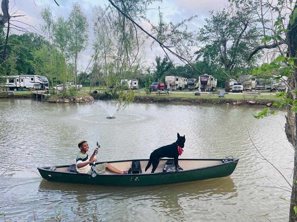 Person canoeing with dog on the pond at Sugar Land RV Park with RVs in background