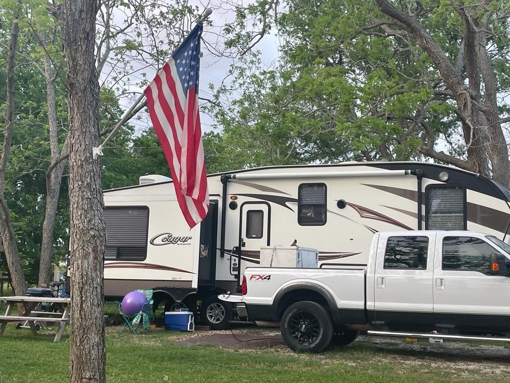 Keystone Cougar fifth-wheel RV with American flag flying at Sugar Land RV Park